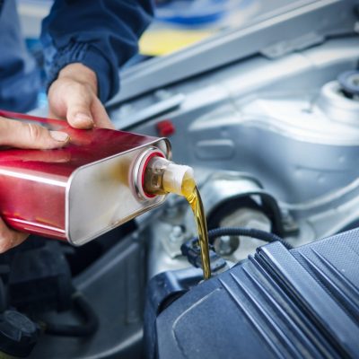 Mechanic changing engine oil on car vehicle.